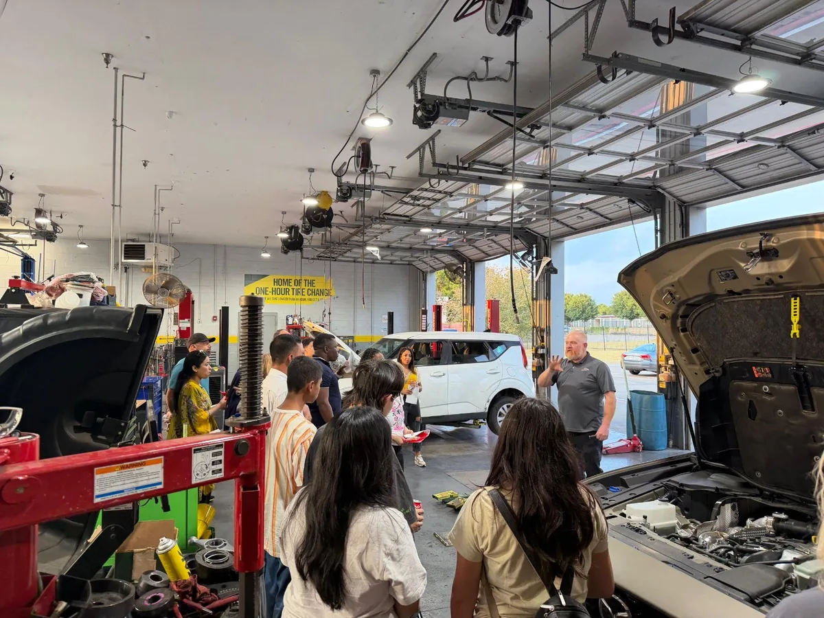 Attendees watching a demonstration in the service bay during an Auto Care 101 class