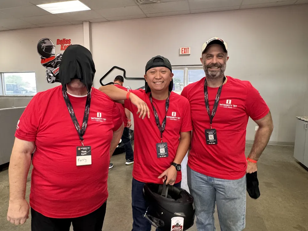 Integrity 1st team members in branded shirts holding helmets at the team race event