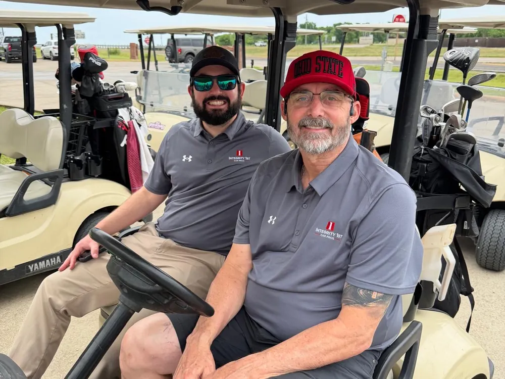 Two Integrity 1st team members in a golf cart at the company tournament
