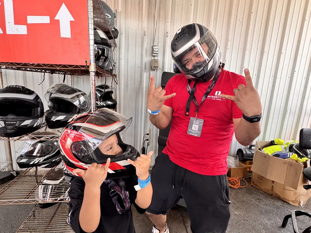 An Integrity 1st team member in a racing helmet giving a thumbs up
